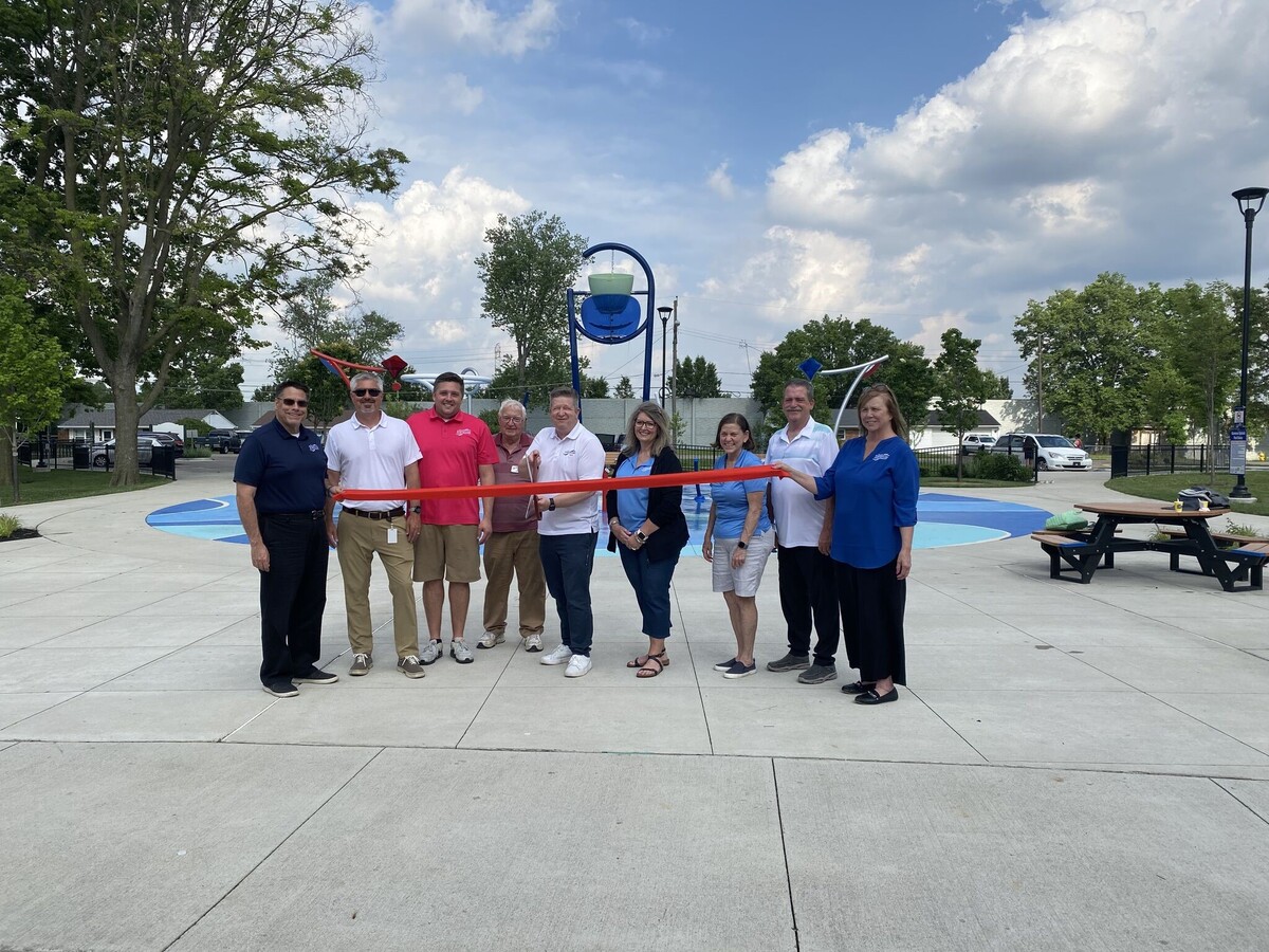 Group doing ribbon cutting in front of park